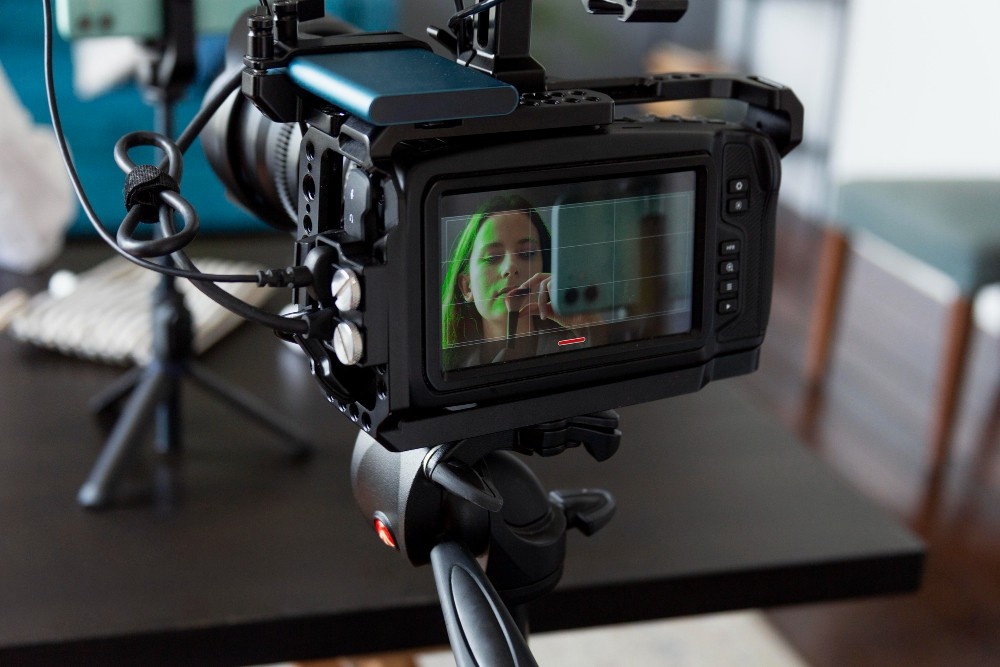 A professional video camera with a monitor showing a woman being filmed, representing the high-quality production services of a Business Videos Agency in Sugar Land