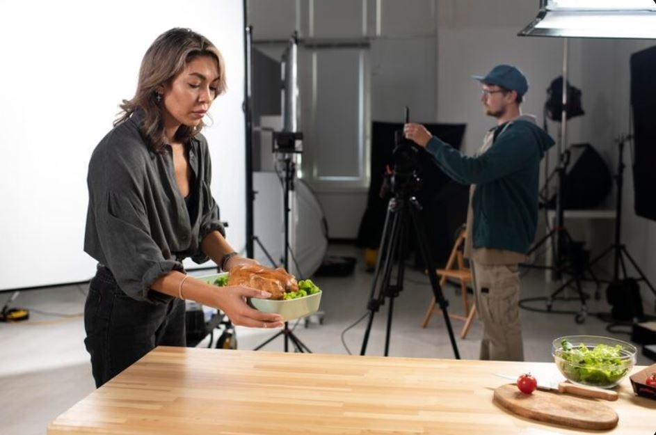 A food stylist prepares a dish while a videographer adjusts the camera, a behind-the-scenes look at a Commercial Video Production Company in Sugar Land
