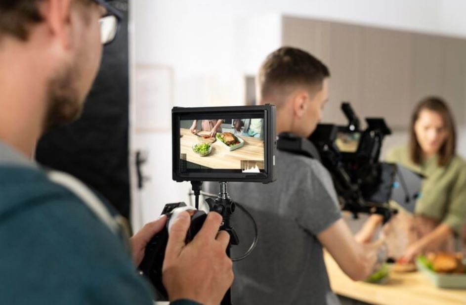 A crew using a professional video camera and monitor to film a cooking scene in a kitchen, a service offered by a Commercial Video Production Company in Woodbridge