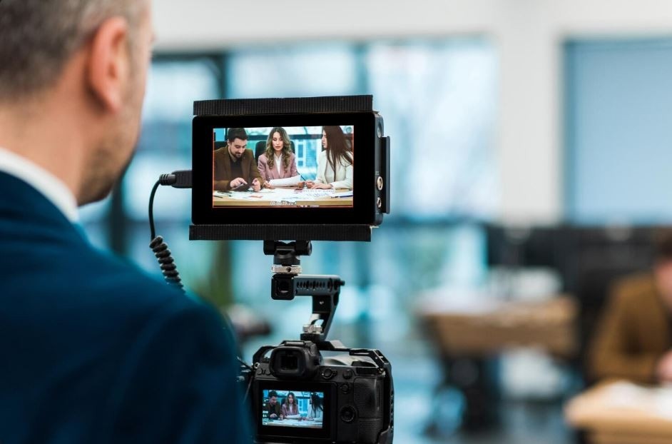 A video production crew member in Sugar Land monitors a live shoot of three business colleagues discussing a project, a service from a Corporate Video Production Agency in Sugar Land