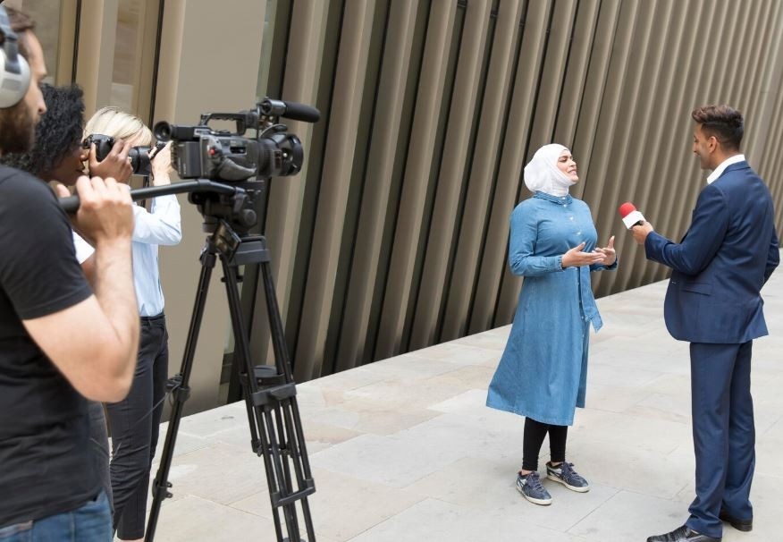 A professional film crew interviews a woman in a hijab for a corporate video, a service provided by a Corporate Video Production Company in Sugar Land