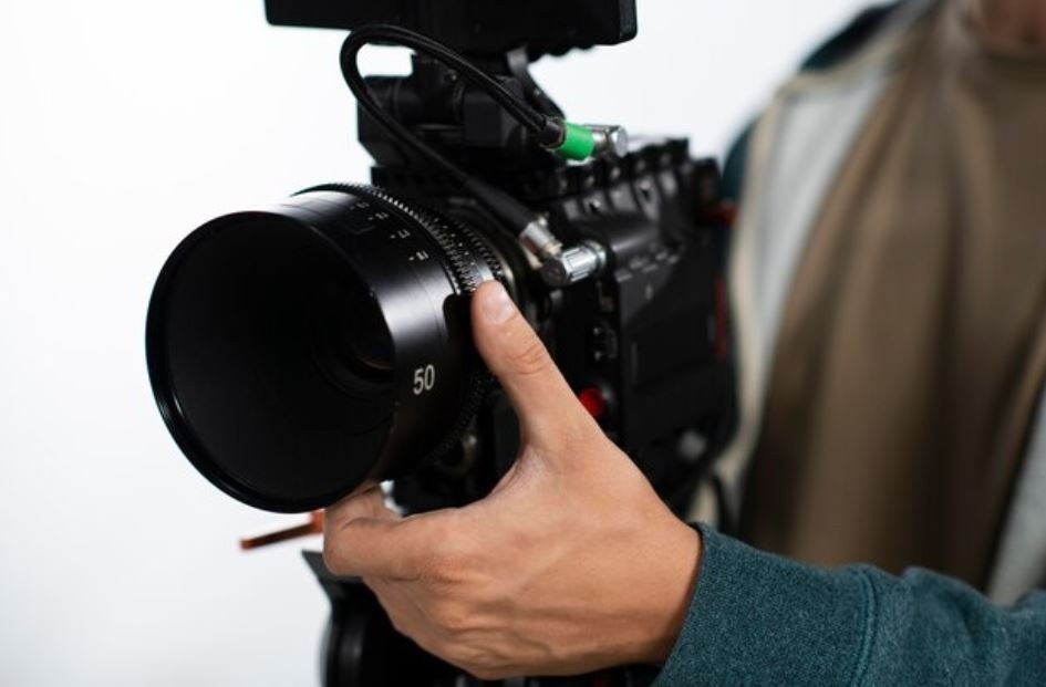 A close-up of a hand adjusting the lens of a professional video camera, representing the high-quality services of a Corporate Video Production company in Sugar Land