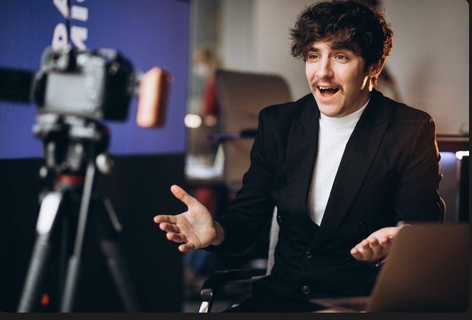 A smiling man in a suit talking animatedly while being filmed by a video camera, representing a professional interview or testimonial by a Business Videos Company in Park Point