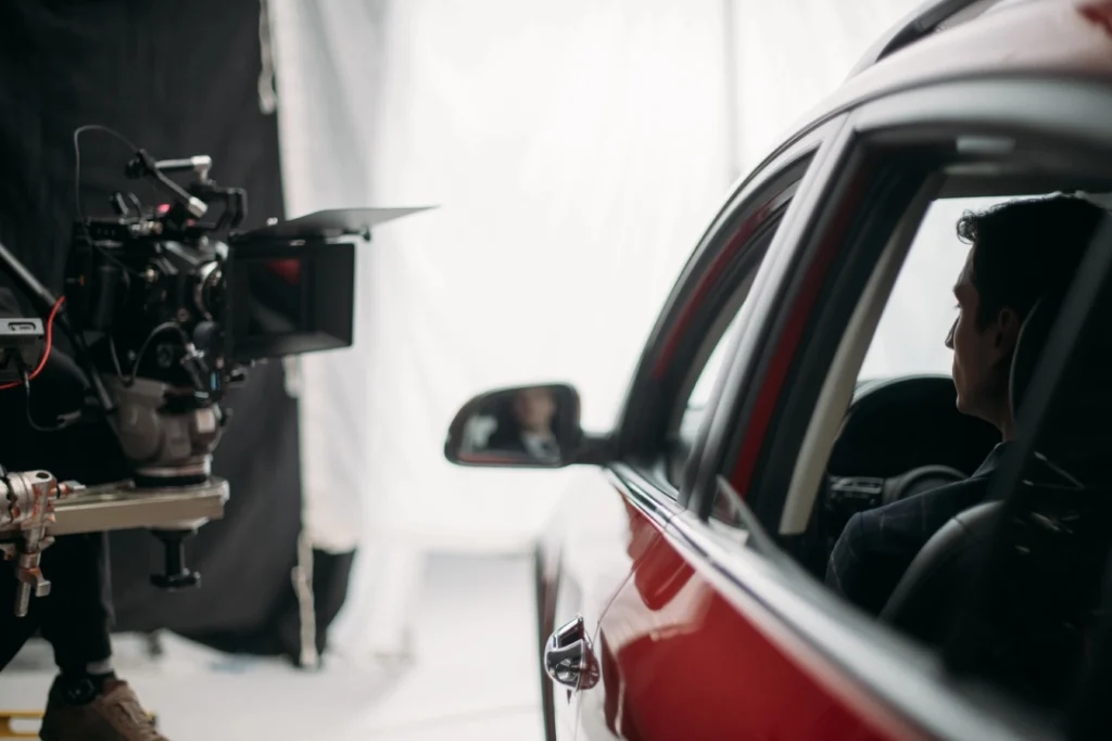Crew films red car scene for commercial video production Sugar Land using stabilizer rig and controlled lighting setup.