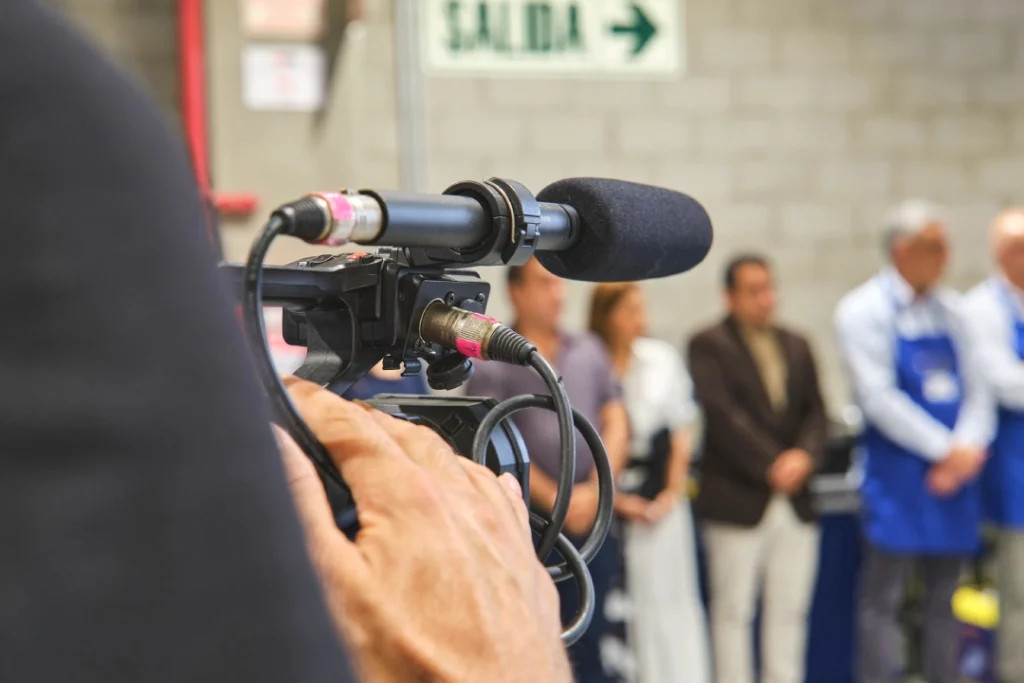 Crew films formal group scene for corporate video production Sugar Land using pro camera and directional microphone.