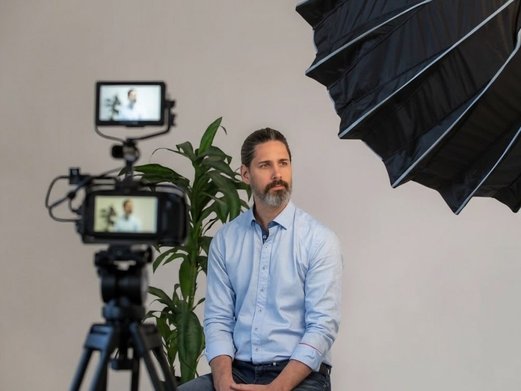 Behind-the-scenes of Sugar Land video production: Director being interviewed in a well-lit studio with umbrella lighting and advanced recording gear for premium content creation.