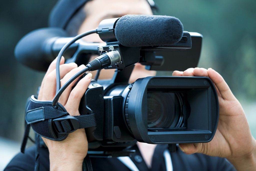 Videographer holding a camera with a professional microphone attached for corporate commercial video production sugar land.