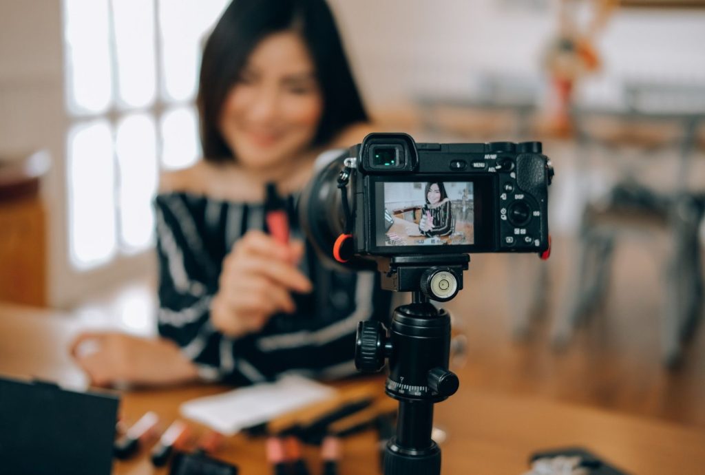 Influencer filming makeup review for promotional videos production Sugar Land using a mirrorless camera on a tripod.