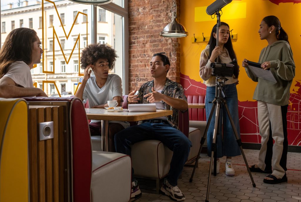 Creative promotional videos company Sugar Land crew filming a lifestyle scene with diverse actors in a vibrant cafe setting.