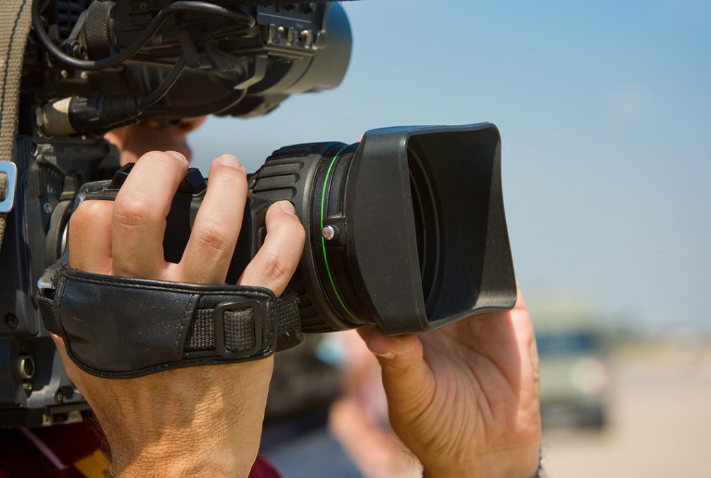 Professional videographer focusing the lens outdoors for commercial video production sugar land services on a sunny day.