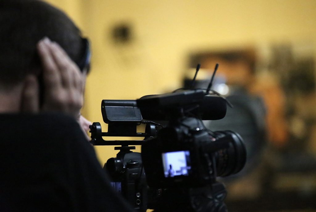Videographer wearing headphones monitoring audio during a shoot for corporate video production company sugar land events.