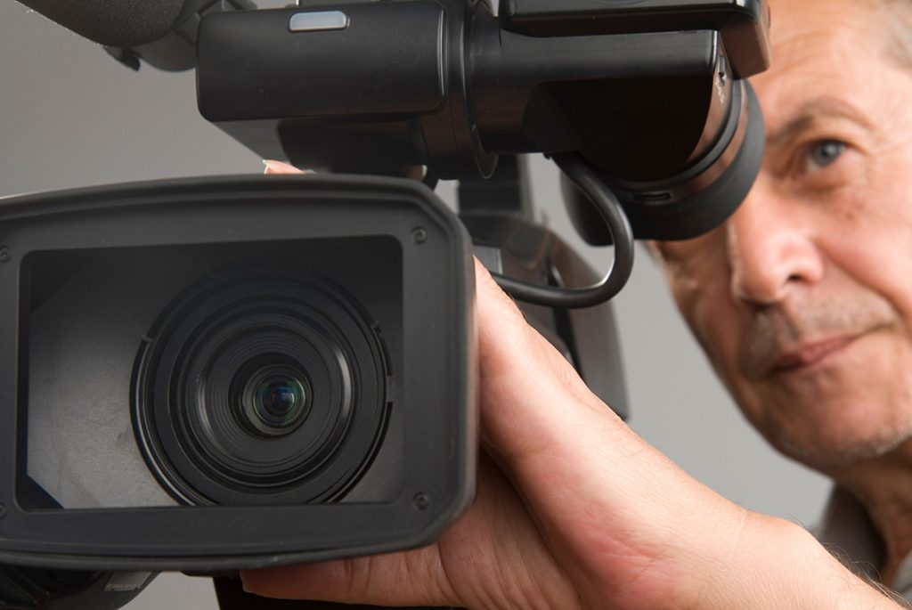 Close-up of camera lens and cameraperson, highlighting professional commercial video production sugar land services for businesses.