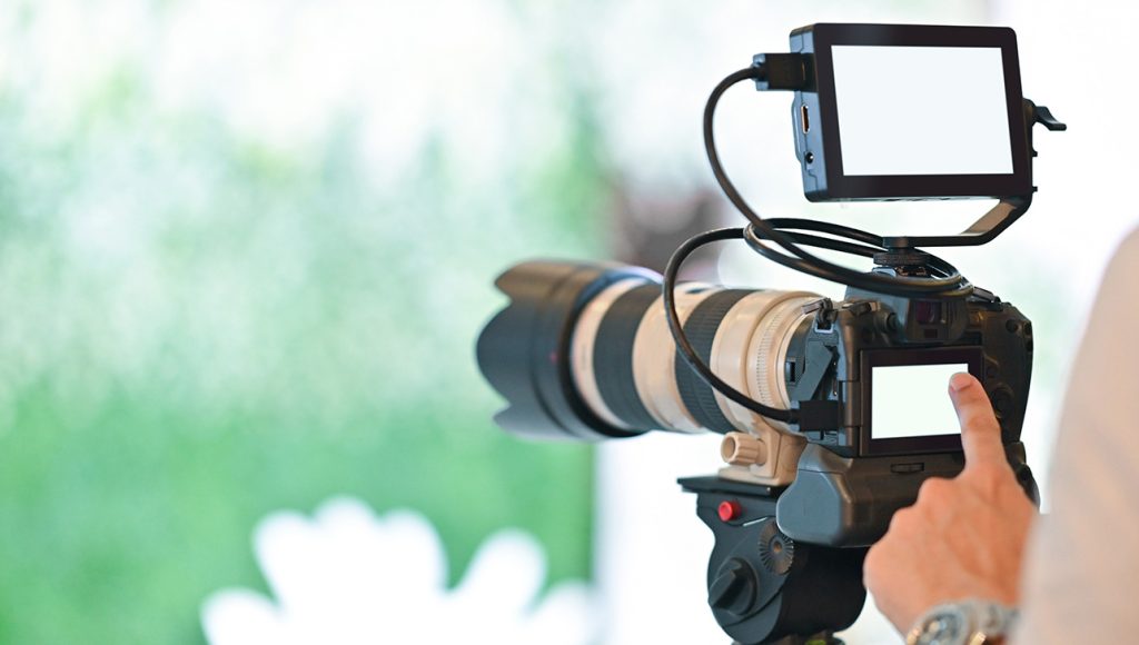 Professional camera with telephoto lens on a tripod, demonstrating quality corporate video production company sugar land services.