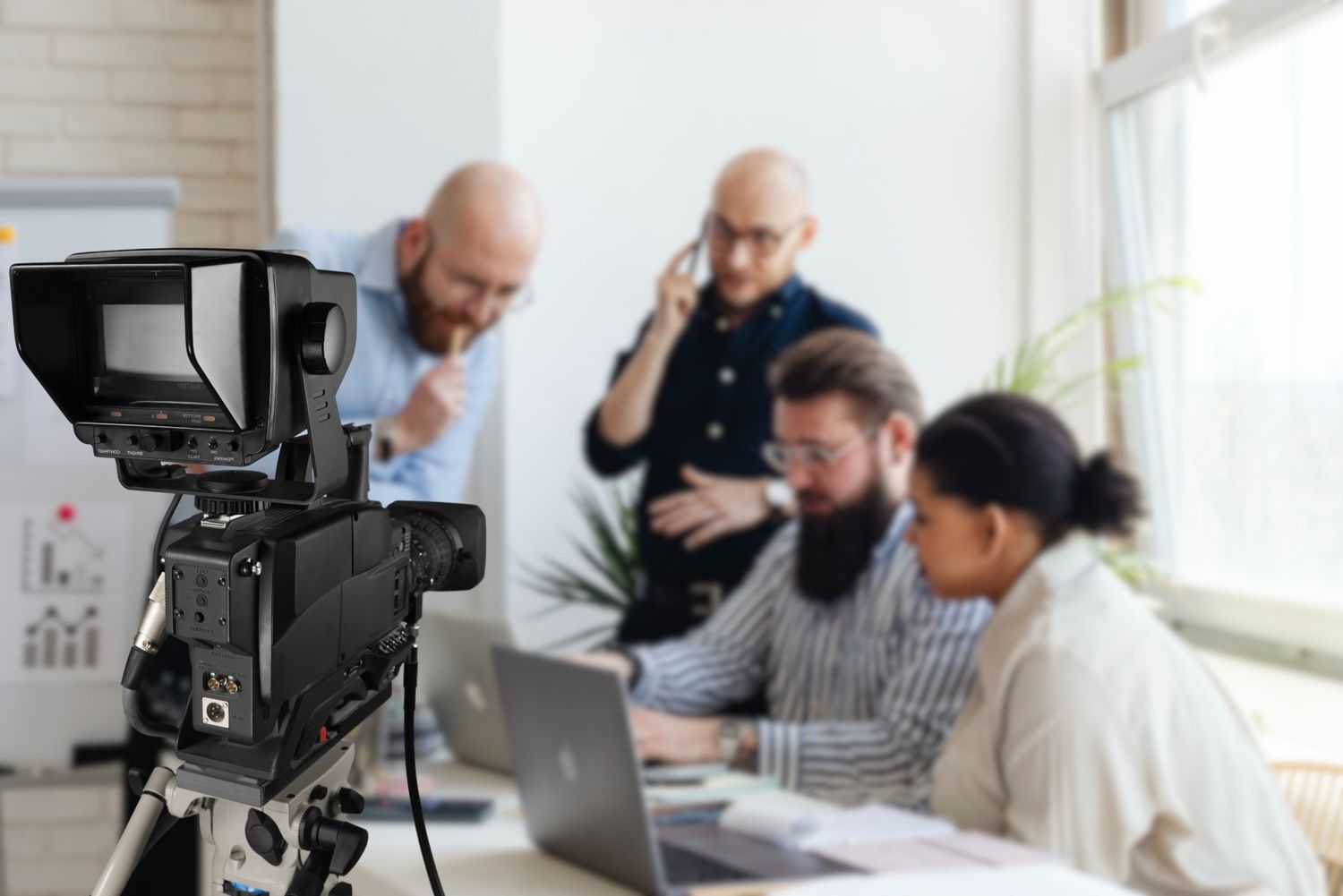 Post-production team meeting at a top corporate video production agency in Sugar Land, reviewing a video edit on a laptop.