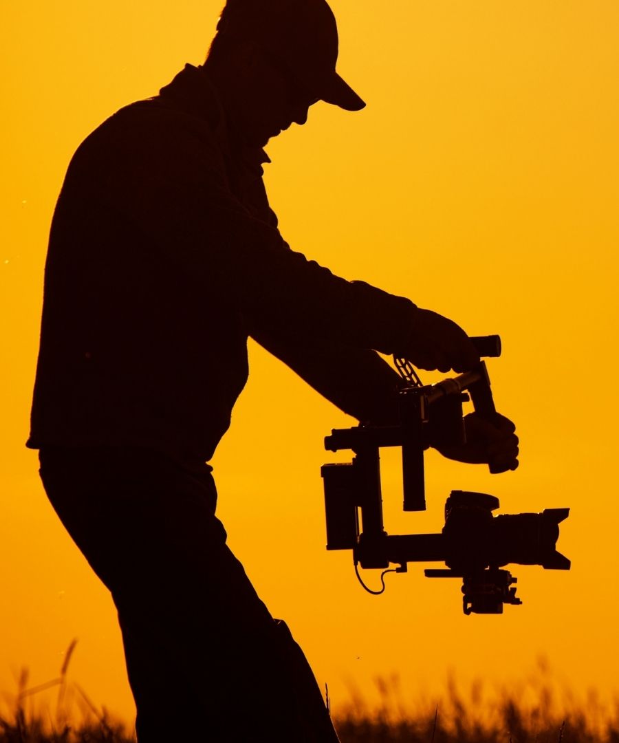 Silhouette of a videographer using a handheld camera gimbal stabilizer at sunset for business marketing videos in Sugar Land.