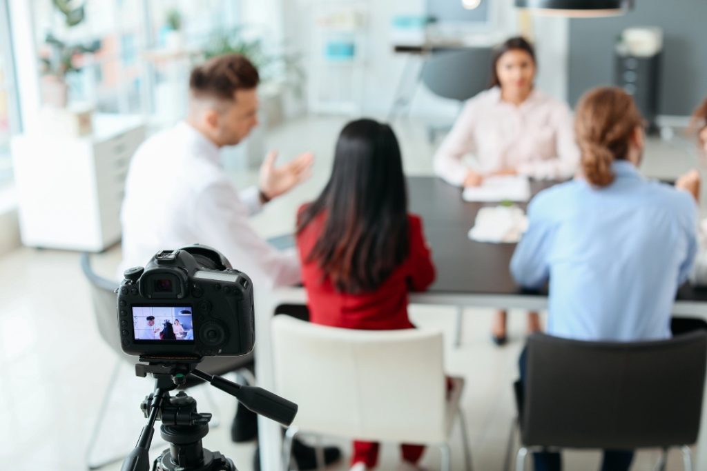 Behind the scenes of corporate video production Sugar Land filming a collaborative business meeting in a bright office.