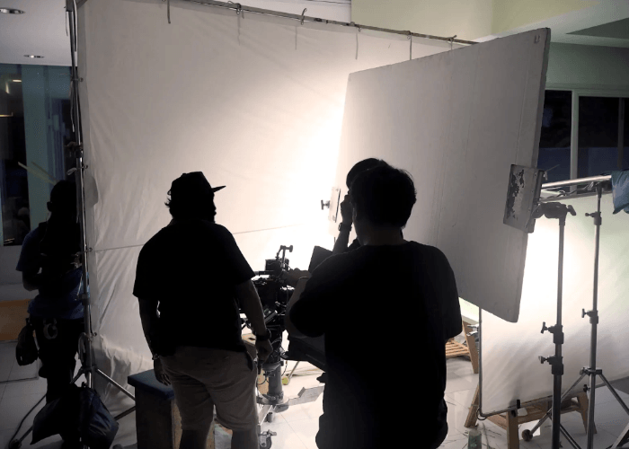 Film crew using professional diffusion panels for commercial video production Sugar Land in a studio environment.