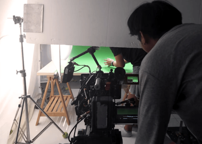 Behind the scenes of commercial video production Sugar Land featuring a green screen studio and lighting gear.