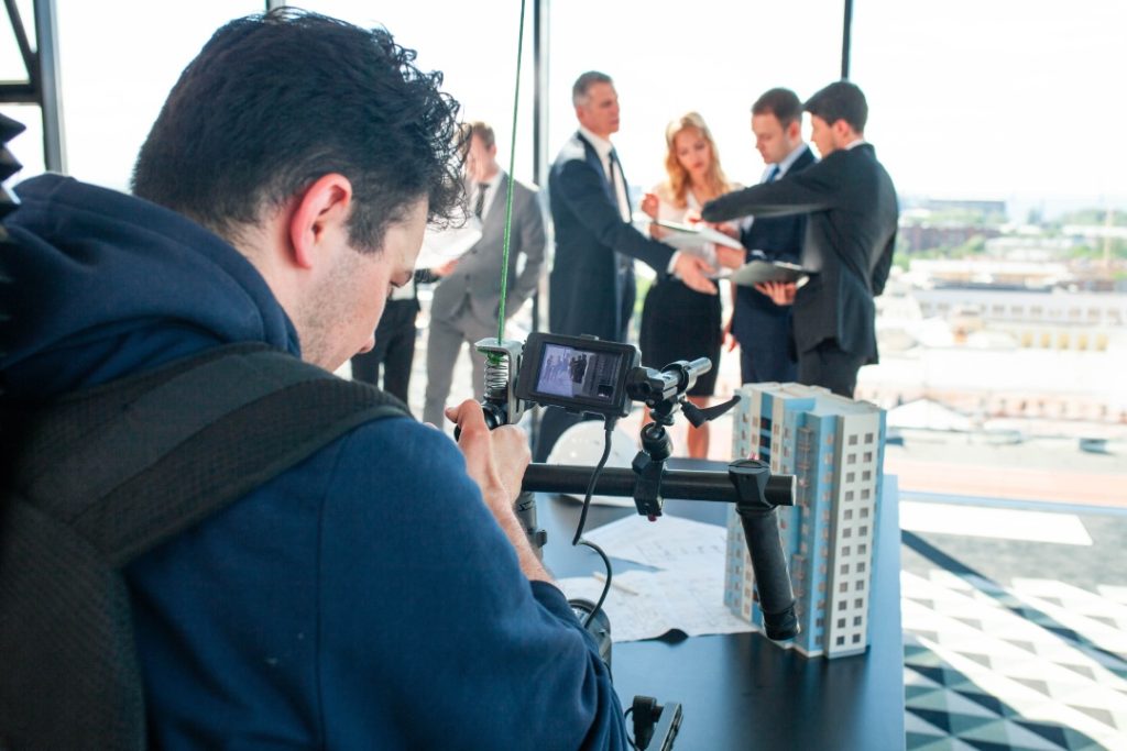 Videographer filming business professionals on set with a video production company Sugar Land crew in a skyscraper.