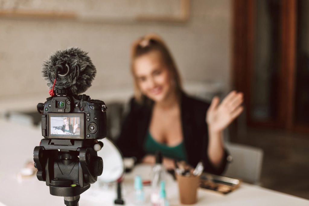 Lifestyle influencer filming a vlog for a promotional videos agency Sugar Land using a DSLR camera and microphone.