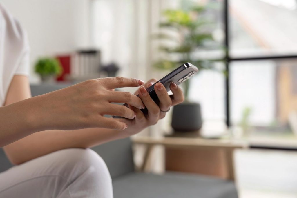 Close up of hands using a smartphone for commercial video production Sugar Land social media marketing campaigns. 