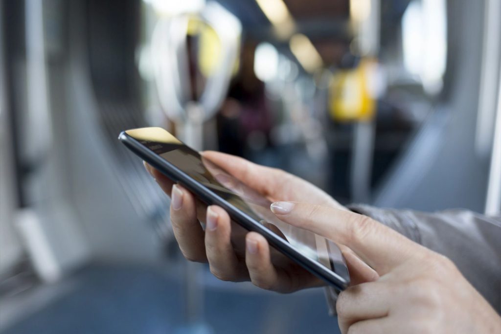 Close up of hands scrolling through commercial video production Sugar Land content while riding on public transit. 