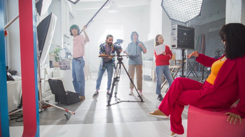 Operator from videography company Sugar Land prepares a professional camera on a dolly for a film shoot with a woman.