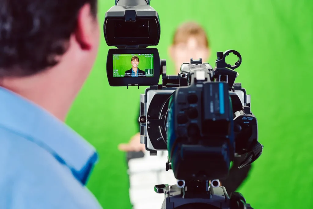 Professional green screen studio setup by a leading video production company sugar land, showing a camera operator and live monitor.
